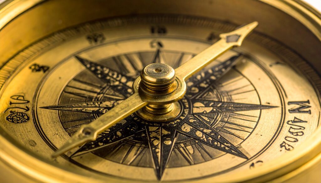 Eine Nahaufnahme einer alten, kunstvollen Kompassnadel aus Messing. Der Kompass liegt jedoch nicht flach, sondern ist in einem 45-Grad-Winkel montiert. Anstelle der Himmelsrichtungen (N, S, O, W) zeigt die Nadel auf vier Symbole, die in das Ziffernblatt eingraviert sind: Ein Gehirn (für kognitive Leistung), ein Herz (für Ausdauer), ein stilisierter Muskel (für Kraft) und eine Wirbelsäule (für Beweglichkeit).